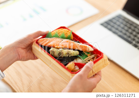 会社のデスクでシャケ弁当を食べるミドル女性 126311271