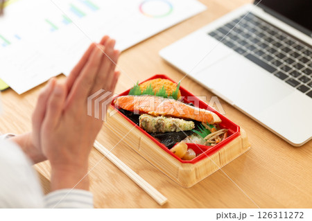 会社のデスクでシャケ弁当を食べるミドル女性 126311272