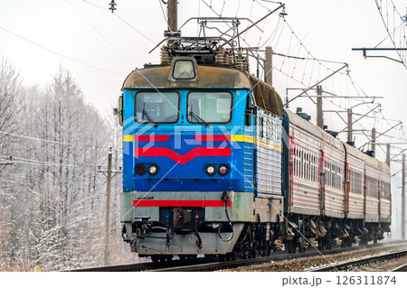 Passenger train hauled by an electric locomotive in winter in Chernihiv Oblast of Ukraine 126311874