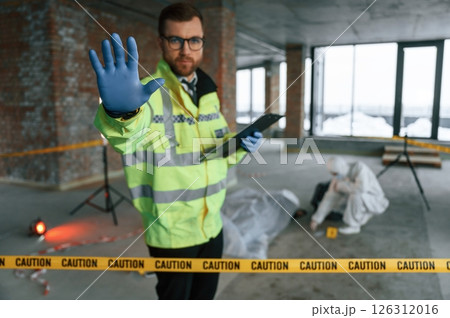 Stop gesture by a hand, no trespassing. Detectives are collecting evidence in a crime scene near dead body Stop gesture by a hand, no trespassing. Detectives are collecting evidence in a crime scene near dead body 126312016