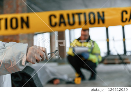 Bullet sleeve in hand. Detectives are collecting evidence in a crime scene near dead body 126312029
