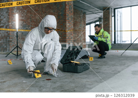 At daytime. Detectives are collecting evidence in a crime scene near dead body At daytime. Detectives are collecting evidence in a crime scene near dead body 126312039