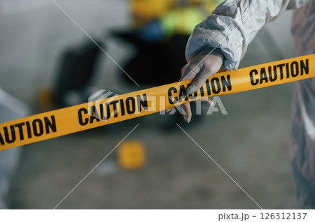Close up view of caution police tape. Detectives are collecting evidence in a crime scene near dead body 126312137