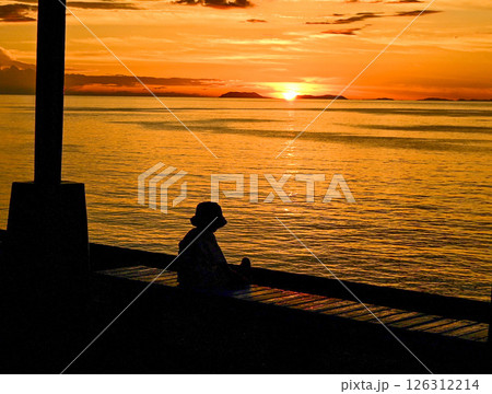 夕暮れの海を見つめる小さな背中 126312214