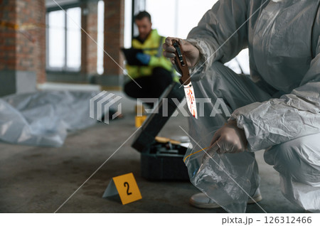 Putting the knife into bag. Detectives are collecting evidence in a crime scene near dead body Putting the knife into bag. Detectives are collecting evidence in a crime scene near dead body 126312466