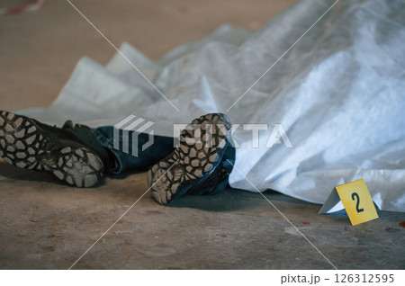 Dead body of a man is on the ground, covered in white cloth. Conception of murder, homicide 126312595