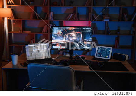 Computer with online first person shooter game launched. In dark room with neon lighting Computer with online first person shooter game launched. In dark room with neon lighting 126312873