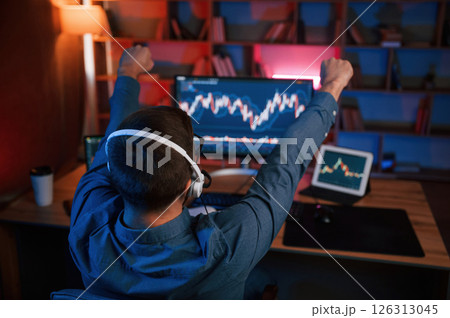 View from behind. Stock trader is working by pc indoors. Conception of exchange and money View from behind. Stock trader is working by pc indoors. Conception of exchange and money 126313045