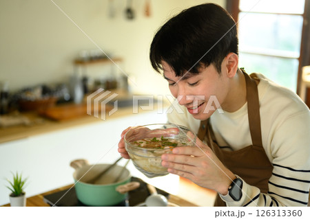 Hands seen seasoning a clear broth soup with meatballs and herbs Hands seen seasoning a clear broth soup with meatballs and herbs 126313360