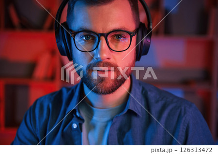 Portrait of man that is in headphones and glasses. Indoors, neon lighting 126313472