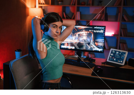 Young pretty female gamer is playing shooter. Neon lighting Young pretty female gamer is playing shooter. Neon lighting 126313630