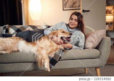 Lying down on the sofa together. Woman is with golden retriever dog at home Lying down on the sofa together. Woman is with golden retriever dog at home 126314092