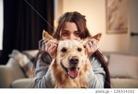 Close up view, portrait. Woman is with golden retriever dog at home 126314102