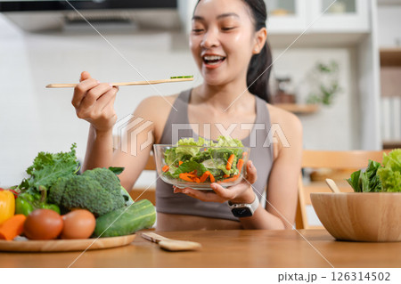 Fit woman enjoys healthy fresh vegetables and fruits breakfast sitting in the kitchen. Fit woman enjoys healthy fresh vegetables and fruits breakfast sitting in the kitchen. 126314502