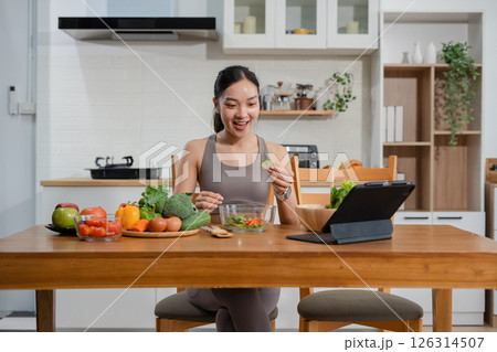 Fit woman enjoys healthy fresh vegetables and fruits breakfast sitting in the kitchen. Fit woman enjoys healthy fresh vegetables and fruits breakfast sitting in the kitchen. 126314507