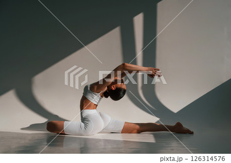 Exercise for the spine. Young caucasian woman with slim body shape is indoors in the studio Exercise for the spine. Young caucasian woman with slim body shape is indoors in the studio 126314576