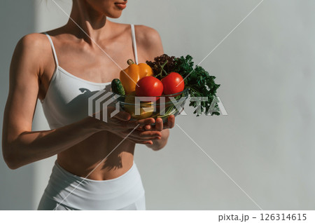 Healthy food. With fruits and vegetables. Young caucasian woman with slim body shape is indoors in the studio Healthy food. With fruits and vegetables. Young caucasian woman with slim body shape is indoors in the studio 126314615