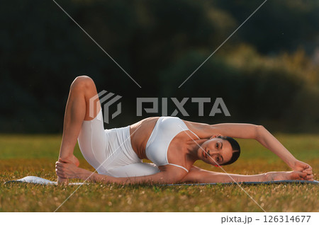 Yoga practice on the mat. Young caucasian woman with slim body shape is in the fitness clothes outdoors 126314677