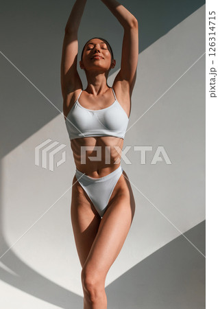 Front view. Standing and posing. Young caucasian woman with slim body shape is indoors in the studio 126314715