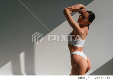 Showing the back. Young caucasian woman with slim body shape is indoors in the studio Showing the back. Young caucasian woman with slim body shape is indoors in the studio 126314719