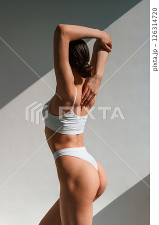 Showing the back. Young caucasian woman with slim body shape is indoors in the studio Showing the back. Young caucasian woman with slim body shape is indoors in the studio 126314720