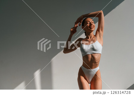 Front view. Standing and posing. Young caucasian woman with slim body shape is indoors in the studio Front view. Standing and posing. Young caucasian woman with slim body shape is indoors in the studio 126314728