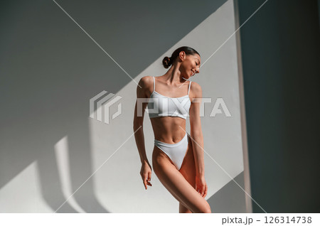 Illuminated by sunlight. Young caucasian woman with slim body shape is indoors in the studio Illuminated by sunlight. Young caucasian woman with slim body shape is indoors in the studio 126314738