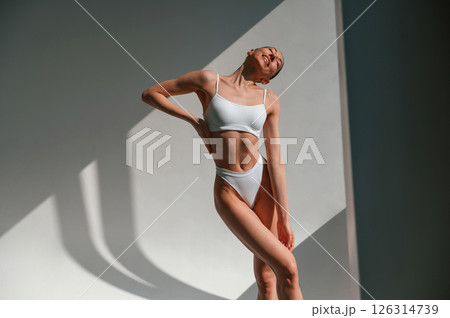 Illuminated by sunlight. Young caucasian woman with slim body shape is indoors in the studio 126314739