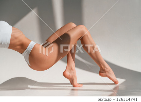 On the legs and hands. Close up view. Young caucasian woman with slim body shape is indoors in the studio 126314741