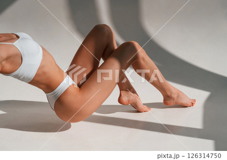 On the legs and hands. Close up view. Young caucasian woman with slim body shape is indoors in the studio 126314750