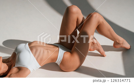 Lying down on the ground. Close up view. Young caucasian woman with slim body shape is indoors in the studio Lying down on the ground. Close up view. Young caucasian woman with slim body shape is indoors in the studio 126314771