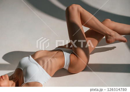 Resting on the floor. Young caucasian woman with slim body shape is indoors in the studio Resting on the floor. Young caucasian woman with slim body shape is indoors in the studio 126314780