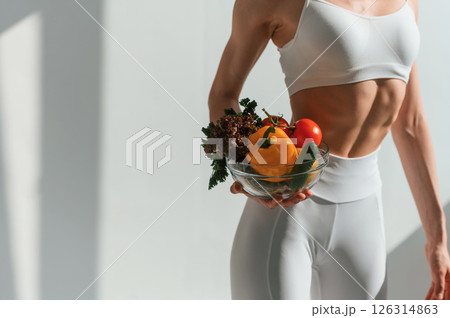 Healthy food. With fruits and vegetables. Young caucasian woman with slim body shape is indoors in the studio 126314863