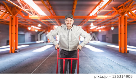 Smiling delivery man pushing an empty hand truck Smiling delivery man pushing an empty hand truck 126314909