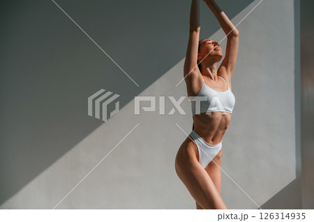 Posing in the sunlight. Young caucasian woman with slim body shape is indoors in the studio Posing in the sunlight. Young caucasian woman with slim body shape is indoors in the studio 126314935