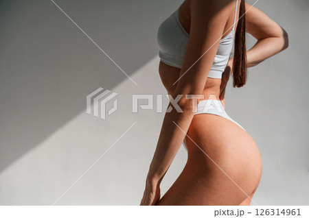 Against wall. Young caucasian woman with slim body shape is indoors in the studio Against wall. Young caucasian woman with slim body shape is indoors in the studio 126314961