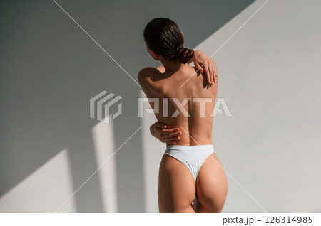 View from the back. Young caucasian woman with slim body shape is indoors in the studio 126314985