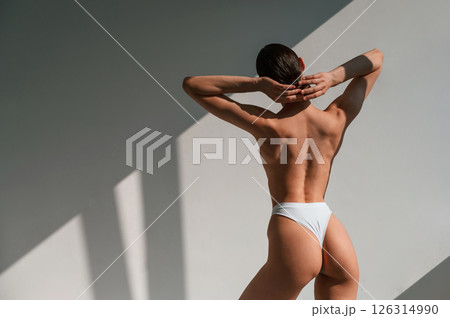Rear view. Young caucasian woman with slim body shape is indoors in the studio 126314990