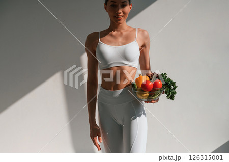 Conception of healthy eating. With fruits. Young caucasian woman with slim body shape is indoors in the studio 126315001