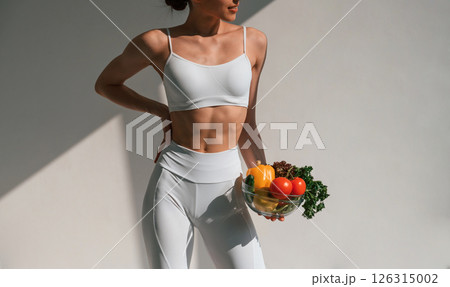 Conception of healthy eating. With fruits. Young caucasian woman with slim body shape is indoors in the studio 126315002