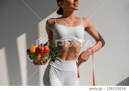 Conception of diet. With vegetalbes and fruits. Young caucasian woman with slim body shape is indoors in the studio Conception of diet. With vegetalbes and fruits. Young caucasian woman with slim body shape is indoors in the studio 126315016