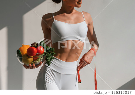 Conception of diet. With vegetalbes and fruits. Young caucasian woman with slim body shape is indoors in the studio 126315017