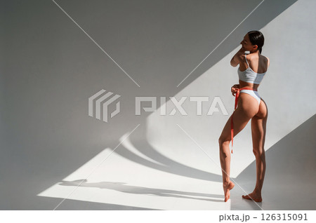 Showing the back. Young caucasian woman with slim body shape is indoors in the studio 126315091