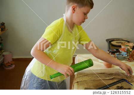 Craftsboy molds clay with rolling pin, closeup. Boy carefully rolls clay with pottery tools in the ceramic studio Craftsboy molds clay with rolling pin, closeup. Boy carefully rolls clay with pottery tools in the ceramic studio 126315552