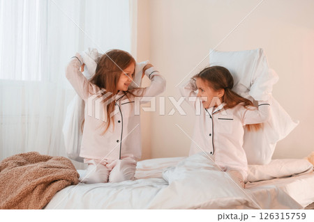 Playing pillow fight. Two little girls are having fun together in domestic room Playing pillow fight. Two little girls are having fun together in domestic room 126315759
