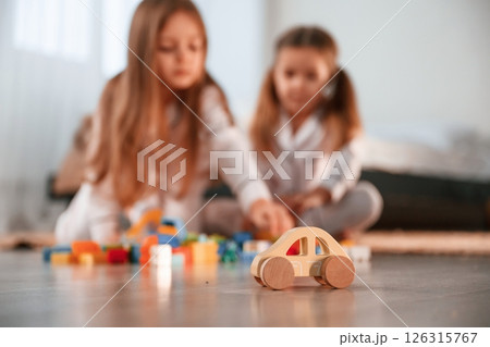 With toys on the floor. Two little girls are playing and having fun together in domestic room 126315767