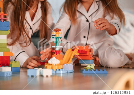 Many of the blocks of plastic construction toys. Two little girls are playing and having fun together in domestic room 126315981