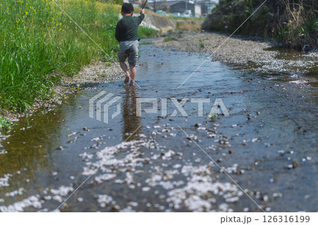 春の日差しの中川遊びをしている少年 126316199