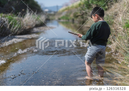 春の日差しの中川遊びをしている少年 126316328