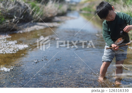 春の日差しの中川遊びをしている少年 126316330